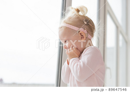 Cochlear implant for baby. Deaf child with hearing aid plays in living room. Health care and medicine technology and innovations - copy space and place for advertising 89647546