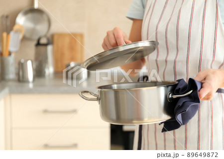 Woman in apron holds metal pot, space for text 89649872
