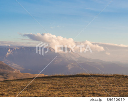 Clouds float on a plateau located in the distance in the mountain valley of the Caucasus 89650059