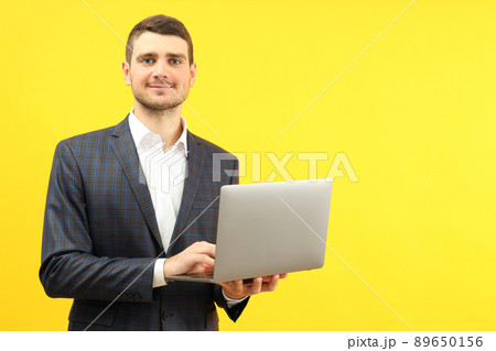 Businessman with laptop on yellow background, space for text Businessman with laptop on yellow background, space for text 89650156