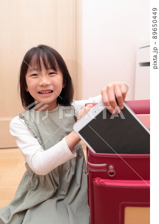 ランドセルからタブレットを取り出す小学1年生の女の子 89650449