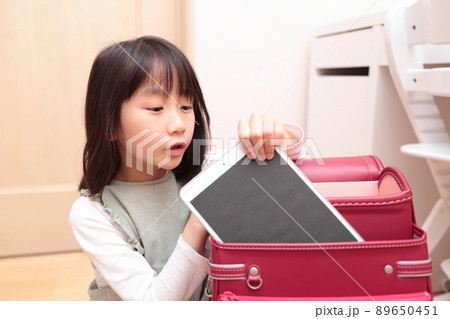 ランドセルからタブレットを取り出す小学1年生の女の子 89650451