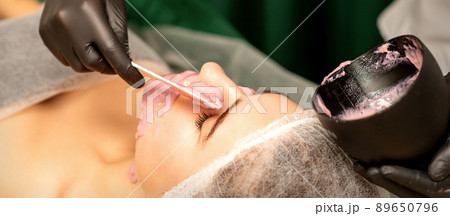 Beautiful young caucasian woman receiving an alginic mask to the face in beauty salon. Facial skin treatment 89650796