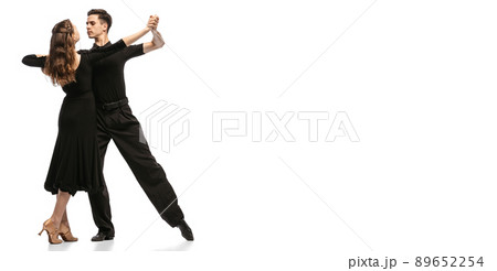 Flyer. Two young graceful dancers wearing black stage outfits dancing ballroom dance isolated on white background. Concept of art, beauty, music, style. 89652254