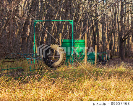 An empty dog playground with training barriers and obstacles made of wheels and wooden crossbars is located in a clearing in the park on a sunny autumn day 89657468