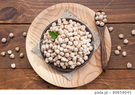 Chickpeas on a wooden plate, wooden spoon on a wooden base Top view. 89658045