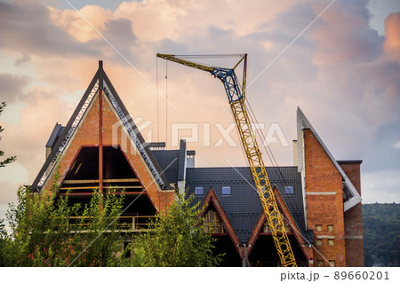 construction site with crane and unfinished cottage in Ukrainian Carpathian village 89660201