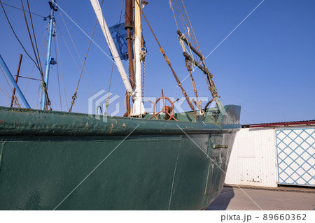 Green boat with red steering wheel and white mastrybatskaya green boat on the seafront. 89660362