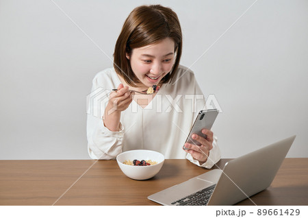 スマホを見ながらオートミールを食べる若いヴィーガン女性 89661429