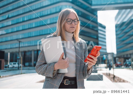 Confident woman talking with somebody on her mobile phone while walking in front of business center Confident woman talking with somebody on her mobile phone while walking in front of business center 89661441
