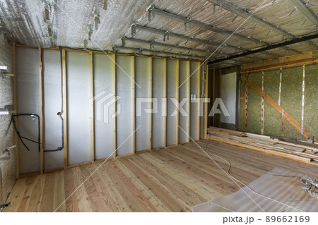Room under construction and renovation with silver aluminum foil on walls and ceiling, oak floor and wooden timber frame for future partition wall. Professional reconstruction and insulation concept. 89662169