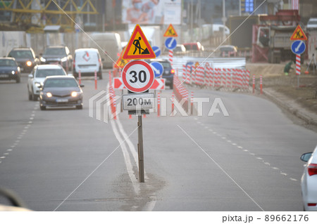 Roadworks warning traffic signs of construction work on city street and slowly moving cars 89662176