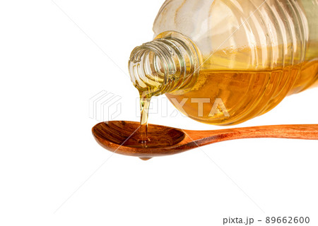 Sunflower oil from a plastic bottle on a wooden spoon over a white background. Sunflower oil from a plastic bottle on a wooden spoon over a white background. 89662600