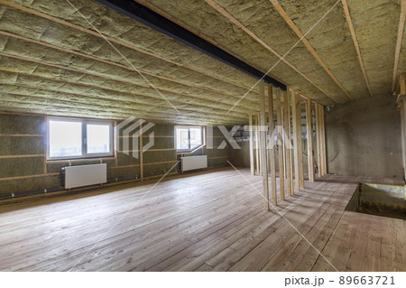 Construction and renovation of big light spacious empty room with oak floor, walls and ceiling insulated with rock wool, heating radiators under low attic windows and wooden frame for future walls. 89663721