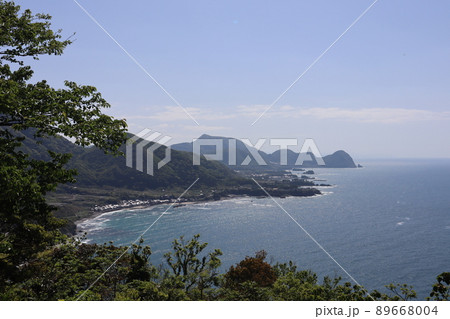 山の上からの青空と雲と青い海面の海とい入り組み連なる半島と浜のある海岸と町の見える風景 山の上からの青空と雲と青い海面の海とい入り組み連なる半島と浜のある海岸と町の見える風景 89668004
