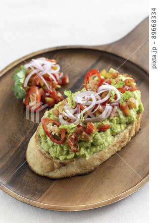 spicy chilli avocado guacamole on toast tapas on wood tray 89668334