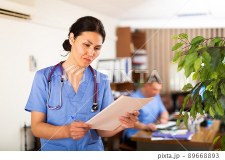 Asian female physician focused on reading of patient case history 89668893