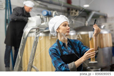 Female brewer using digital hydrometer for measuring beer density 89669005