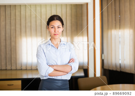 Successful business woman standing with arms crossed in office Successful business woman standing with arms crossed in office 89669092