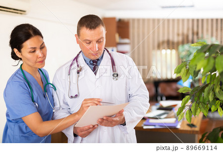 Two doctors checking patient papers in clinic Two doctors checking patient papers in clinic 89669114