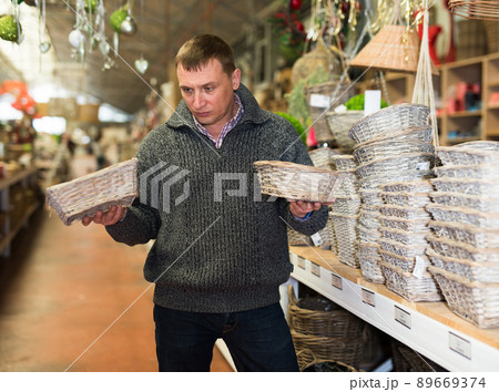 Puzzled man choosing wickerwork in shop 89669374