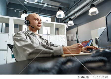 Young bald man working in a call center office Young bald man working in a call center office 89670656