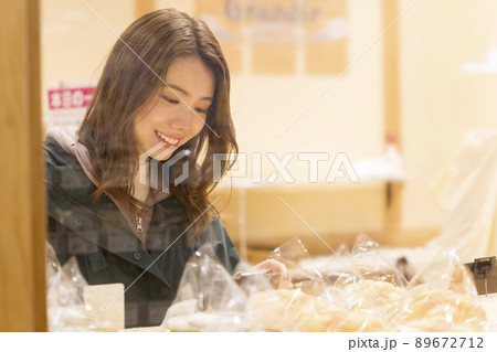 パン屋さんでパンを選ぶ若い女性 89672712