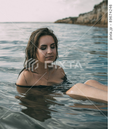 Elegant woman sit in the water. Sunset. The concept of unity with nature. 89674246