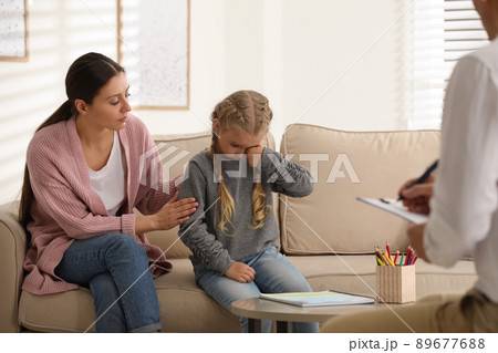 Little girl and her mother on appointment with child psychotherapist indoors Little girl and her mother on appointment with child psychotherapist indoors 89677688
