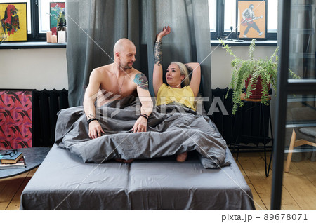 Modern mature Caucasian man and woman in love waking up together in loft bedroom in morning 89678071