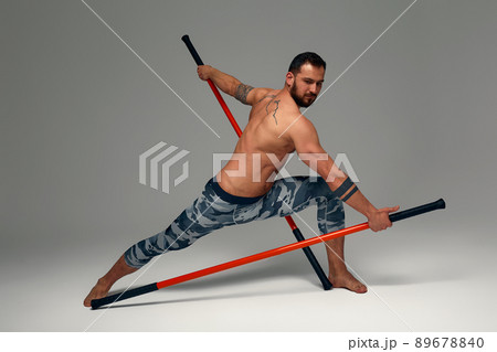A ninja man holds on to a fighting stick and attacks close-up on gray studio background 89678840