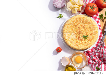 Traditional Spanish omelette with potatoes and onion with ingredients on white background with copy space, flat lay. Spanish tapas. 89679517