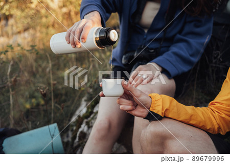 Two Travelers Man and Woman Made a Stop During the Hike to Drink Hot Tea from the Thermos Two Travelers Man and Woman Made a Stop During the Hike to Drink Hot Tea from the Thermos 89679996