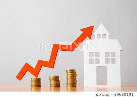 Coins on a table, a red up arrow and house. The concept of the rising price of real estate Coins on a table, a red up arrow and house. The concept of the rising price of real estate 89680191