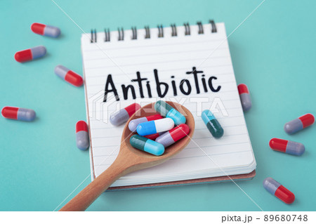 Antibiotic medicine concept, capsule pills on spoon with notebook on green background 89680748