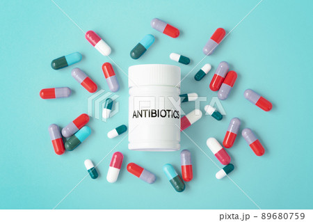 Antibiotics concept, heap of capsule pills with antibiotic medicine bottle on green background, top view 89680759