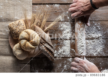 Bread with wheat ears and flour on wood board, top view Bread with wheat ears and flour on wood board, top view 89683186