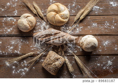 Bread with wheat ears and flour on wood board, top view. Bread with wheat ears and flour on wood board, top view. 89683187