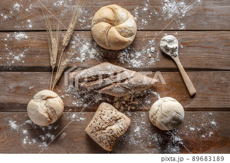 Bread with wheat ears and flour on wood board, top view. Bread with wheat ears and flour on wood board, top view. 89683189