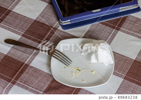empty white dish with leftovers of eaten food, crumpled table-napkin and steel fork 89683238