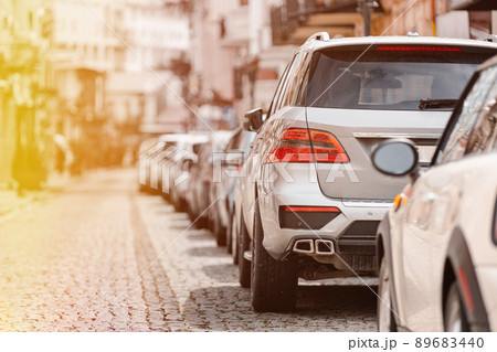 Many Cars parked in row on street in city in sunny summer day. ecological problem - air pollution 89683440