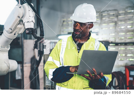African American factory worker working with adept robotic arm 89684550