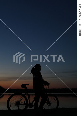 Silhouette of woman with mountain bike on colorful blue sky sunset background. Active outdoors lifestyle Silhouette of woman with mountain bike on colorful blue sky sunset background. Active outdoors lifestyle 89684584