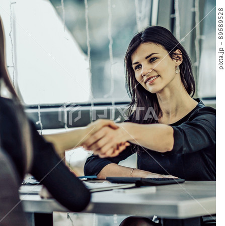 Two Businesswomen Shaking Hands In Modern Office Two Businesswomen Shaking Hands In Modern Office 89689528