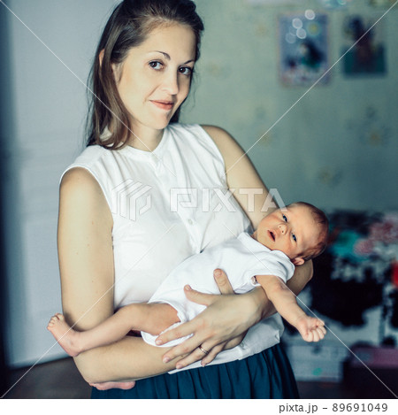 concept of motherhood:a portrait of a young mother with a newbor concept of motherhood:a portrait of a young mother with a newbor 89691049