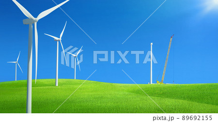 Windfarm in a field of green grass with construction crane installing wind turbine against blue sky Windfarm in a field of green grass with construction crane installing wind turbine against blue sky 89692155