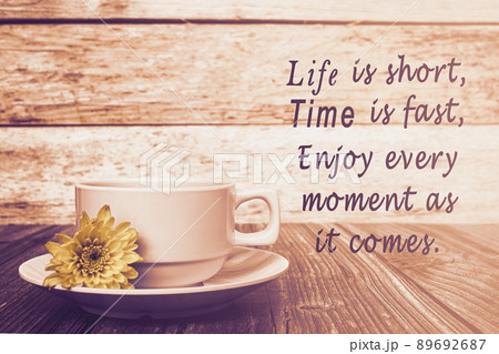 Motivational quote with coffee cup and flowers on wooden table. 89692687