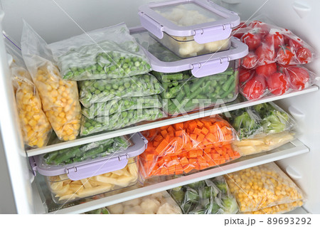 Plastic bags and containers with different frozen vegetables in refrigerator Plastic bags and containers with different frozen vegetables in refrigerator 89693292