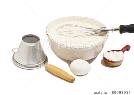 MIxing baking ingredients in a bowl,with egg, dry yeast and sieve for sifting flour isolated on white background 89693957