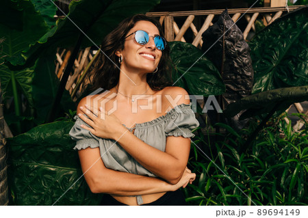 Trendy young ethnic lady admiring beautiful exotic garden Trendy young ethnic lady admiring beautiful exotic garden 89694149